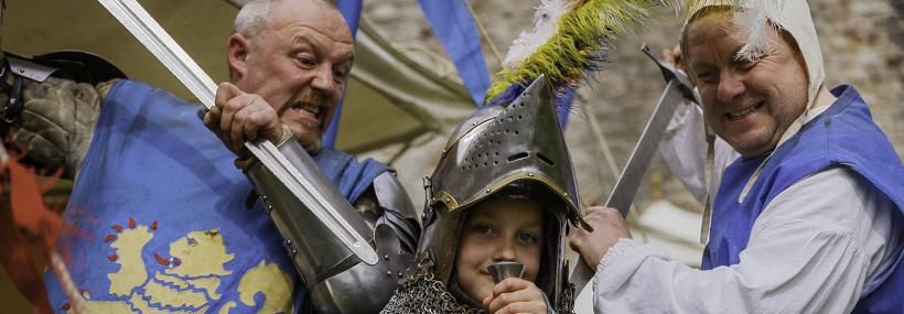 Ymwelydd ifanc yn sefyll gyda dau farchog/young visitor posing with two knights